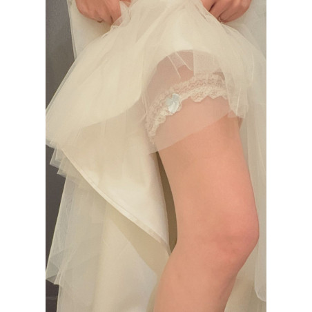 Jarretière de mariée en dentelle blanche, avec un petit nœud en ruban bleu.